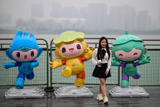 A woman poses for photographs with the 2022 Asian Games mascots (left to right) Chenchen, Congcong and Lianlian along the promenade of Qiantang river in Hangzhou in China's eastern Zhejiang province on Sept. 22, 2023.