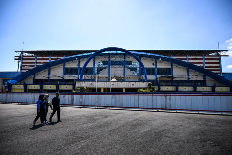 This picture taken on Sept. 21, 2023 shows people walking past the Kanjuruhan football stadium, where 135 people died in a stampede on October 1, 2022, in Malang, East Java. The Indonesian stadium where 135 people died in October 2022 in one of football's worst tragedies lies empty but intact, despite government pledges to demolish it and rebuild a safer site.