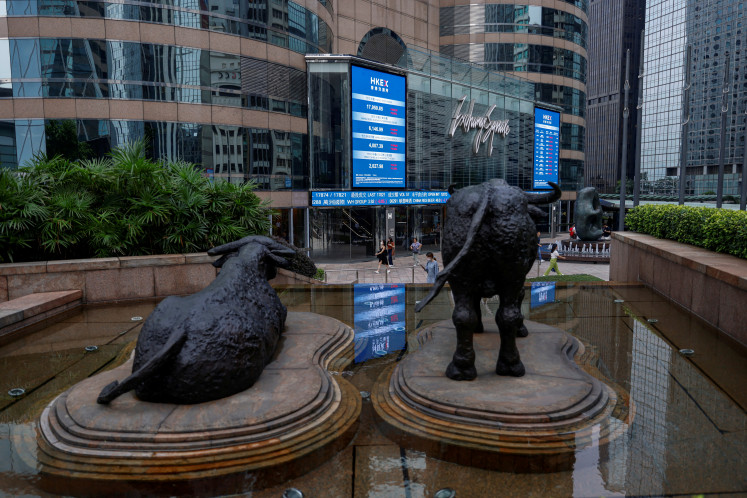 Bull statues are placed in font of screens showing the Hang Seng stock index and stock prices outside Exchange Square in Hong Kong, China, on Aug. 18, 2023.
