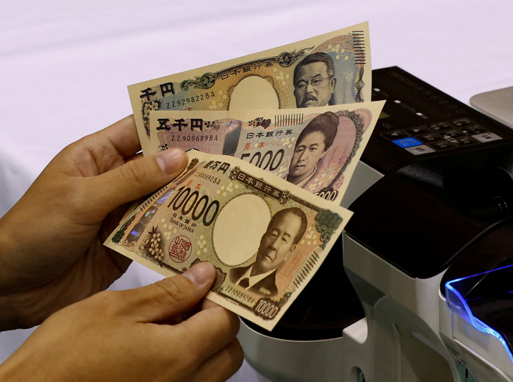 A worker holds samples of new Japanese yen banknotes in Tokyo on Nov. 21, 2022 at a factory of the National Printing Bureau at a media event about the new notes scheduled to be introduced in 2024.