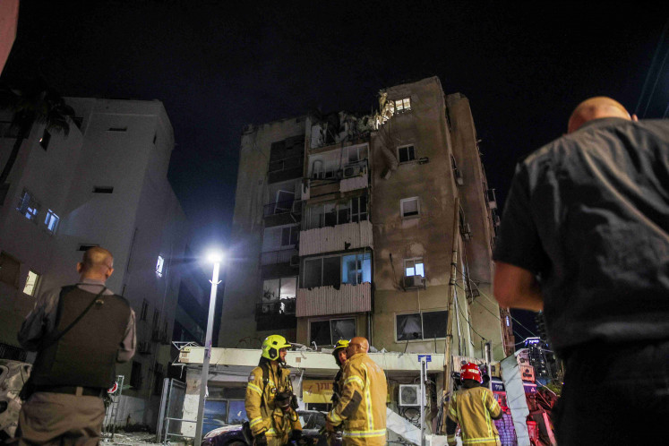 Firefighters talk below a building that was hit by a rocket launched from the Gaza Strip, in Tel Aviv, Israel October 7, 2023.