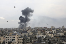 A plume of smoke rises above buildings in Gaza City during an Israeli air strike, on October 9, 2023. Israel relentlessly pounded the Gaza Strip overnight and into October 9 as fighting with Hamas continued around the Gaza Strip, as the death toll from the war against the Palestinian militants surged above 1,100.

