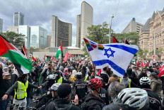 People carry Palestinian flags near an Israeli flag of a counter-protester during a rally in front of City Hall in Toronto, Ontario, Canada October 9, 2023. 