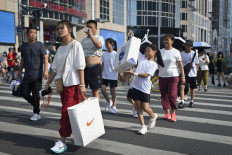 Pedestrians cross a street at a business district in Beijing on August 14, 2023.