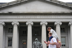 People pass by the Treasury Building on Pennsylvania Avenue in Washington, DC, on May 19, 2023.