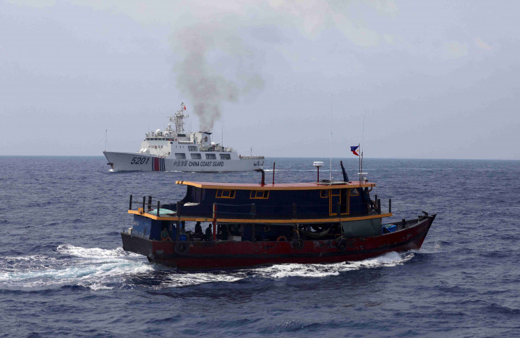 A Philippine supply boat sails near a Chinese Coast Guard ship during a resupply mission for Filipino troops stationed at a grounded warship in the South China Sea, Oct. 4, 2023. REUTERS/Adrian Portugal