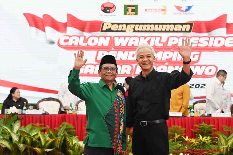 Presumptive presidential nominee from the Indonesian Democratic Party of Struggle (PDI-P) Ganjar Pranowo (right) and his runnning mate Mahfud MD wave after the party named the latter as the presumptive vice-presidential candidate at the PDI-P headquarters in Jakarta on Oct. 18, 2023.
