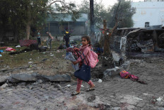 A girl carrying her belongings walks in the area of Al-Ahli hospital where hundreds of Palestinians were killed in a blast that Israeli and Palestinian officials blamed on each other, and where Palestinians who fled their homes were sheltering amid the ongoing conflict with Israel,  in Gaza City, October 18, 2023. 
