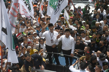 Presidential nominee from the Coalition for Change electoral alliance Anies Baswedan (left) and his running mate Muhaimin Iskandar wave to the press upon arriving at the General Elections Commission (KPU) headquarters in Central Jakarta on Oct. 19, 2023. The pair registered their bid on the first day of the presidential-candidate registration period, slated for Oct. 19 to 25.