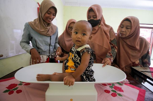 Weight of responsibility: Community health workers weigh a toddler during a regular mother-and-child checkup on Oct. 12, 2023, at a posyandu (integrated health post) in South Celep district, Sidoarjo, East Java.
