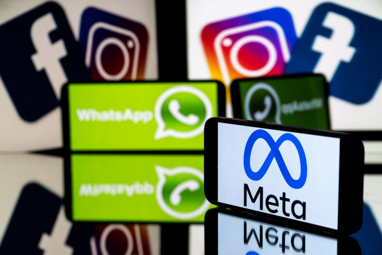 This picture taken on January 12, 2023 in Toulouse, southwestern France shows a smartphone and a computer screen displaying the logos of the Instagram, Facebook, WhatsApp and their parent company Meta. 
