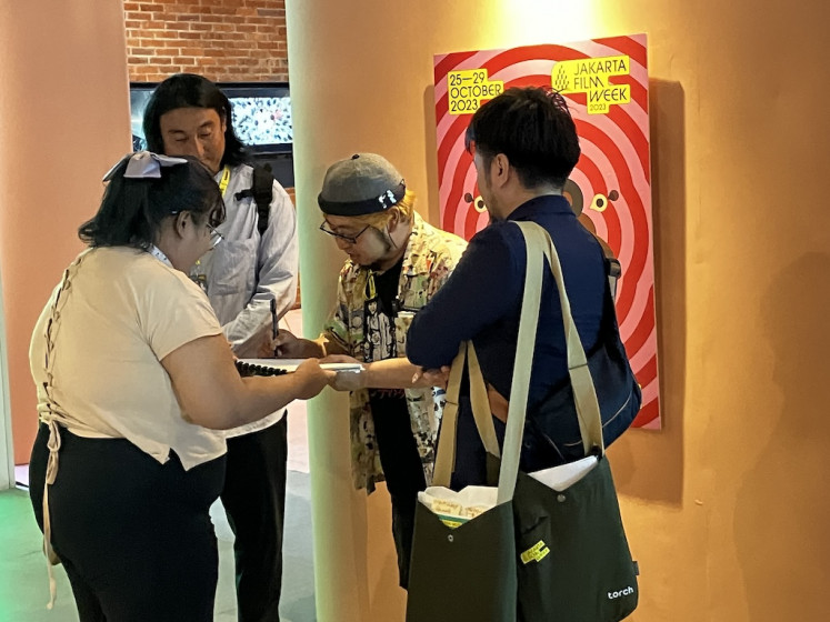 Saluting horror: Japanese filmmaker and acclaimed horror auteur Takashi Shimizu (second right) signs an autograph for a fan. His most recent horror flick, 'Sana’, was screened in Jakarta Film Week 2023. 