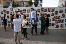 People stand next to the wall with pictures, dedicated to hostages that are being held in Gaza after they were kidnapped from Israel by Hamas gunmen on October 7, as families and supporters of hostages hold a demonstration calling for their immediate release in Tel Aviv, Israel November 3, 2023.