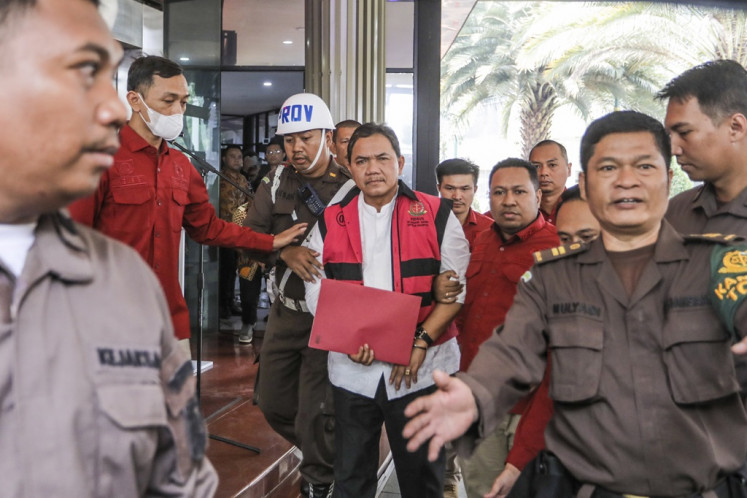 Supreme Audit Agency (BPK) member Achsanul Qosasi (center) is escorted out of the Attorney General's Office (AGO) headquarters on Nov. 3, 2023, after investigators arrested him. The AGO alleges that he received Rp 40 billion (US$2.5 million) in kickbacks pertaining to the botched procurement for the 4G telephony project.