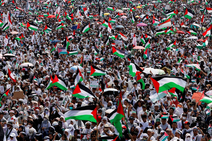 People wave Palestinian and Indonesian flags on Nov. 5, 2023 to show support for Palestinians in Gaza during a rally at Merdeka Square in Central Jakarta.