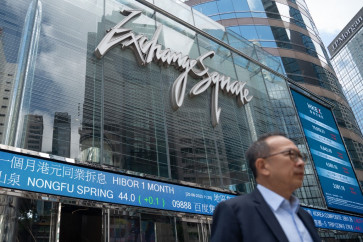 A man walks past an electronic sign displaying stocks at Exchange Square in Hong Kong, China, on June 20, 2023. 