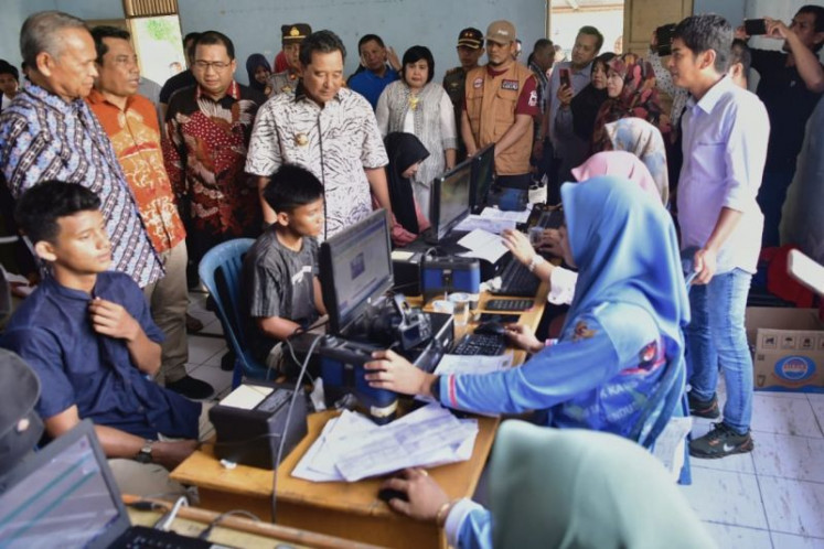 Three young people have their electronic identification cards (e-KTP) made while South Sulawesi’s acting governor Bahtiar Baharuddin (fourth left) looks on, during an inspection of a local government facility in Luwu, South Sulawesi on Nov. 5, 2023. People under 40, including first-time voters, will make up the majority of voters in the 2024 elections, according to the General Elections Commission (KPU).