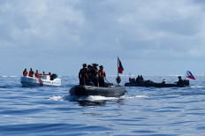 This photo taken on Nov. 10, 2023 shows Philippine Navy personnel (right) clearing the way from the China Coast Guard (left) for the journalists and Philippine coast guard personnel (center) onboard the rigid inflatable boat at Second Thomas Shoal in the South China Sea on the same day. China Coast Guard vessel (left) blocks the ML Kalayaan chartered supply boat (right) during a mission to deliver provisions at Second Thomas Shoal in the South China Sea on Nov. 10.