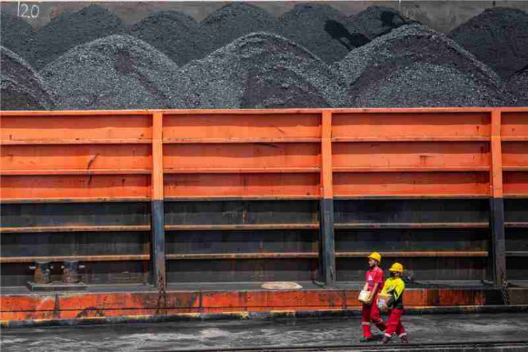 Workers walk near a tugboat carrying coal barges at a port in Palembang, South Sumatra province, Indonesia, January 4, 2022.