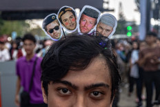 A fan of British rock band Coldplay wears a headband with pictures of band members at the entrance of the Gelora Bung Karno Stadium before the world tour concert in Jakarta on November 15, 2023. 