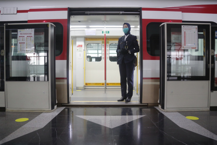 A Jakarta light rail transit (LRT) attendant stands inside a train on June 9, 2020 at Velodrome Station in Rawamangun, East Jakarta, ready to welcome passengers after the rail service reopened with a limited capacity of 30 passengers per car.