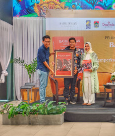 Joint project: A representative of Gramedia book publisher (left) hands over the book 'Batik Durian Lubuklinggau: Memperkaya Khazanah Batik Nusantara' to co-writers Rai Rahman Indra (center) and Yetti Oktarina Prana in Gramedia, Central Jakarta, on Oct. 15, 2023. 