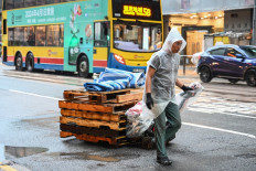 A delivery worker pulls pallets up a street in the rain in Hong Kong on Oct. 18, 2023.