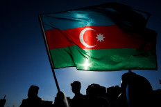 Schoolchildren wearing traditional dresses wave an Azerbaijani flag during the annual Day of Reading event outside the Heydar Aliyev Cultural Center in Baku on April 26, 2018.