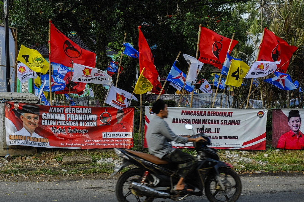 A motorcycle rider passes through a row of election campaign banners in Lebak regency, Banten, on Dec. 11, 2023. The General Elections Commission (KPU) is restricting candidates from putting up campaign banners in public infrastructure such as public parks and pedestrian bridges.