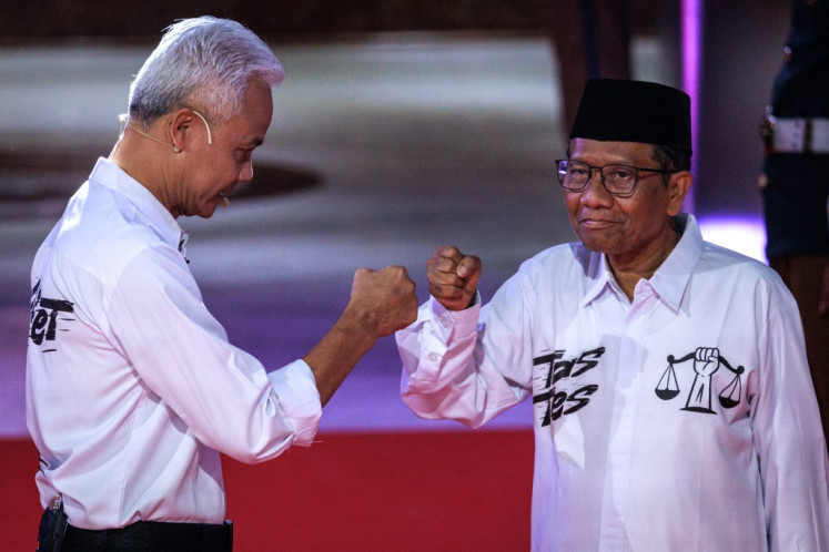 Presidential candidate and former Central Java governor Ganjar Pranowo (left) and vice presidential candidate Mahfud MD react as they arrive to attend the first presidential election debate at the General Elections Commission (KPU) office in Jakarta on Dec. 12, 2023.