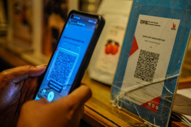 A person uses a smartphone on Dec. 9, 2023, to scan a Quick Response Indonesian Standard (QRIS) code to complete a transaction at a shop in Rangkasbitung, Banten.