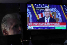 A trader works, as a screen displays a news conference by Federal Reserve Board Chairman Jerome Powell following the Fed rate announcement, on the floor of the New York Stock Exchange (NYSE) in New York City, US, December 13, 2023. 