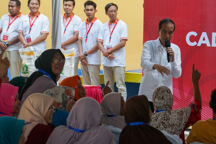 President Joko “Jokowi“ Widodo (right, with mic) talks to an audience member on Dec. 13, 2023 at an event in Pekalongan, Central Java, where he symbolically distributed 10,000 kilograms of rice to 1,000 local families while on an inspection visit to the local State Logistic Agency (Bulog) warehouse.