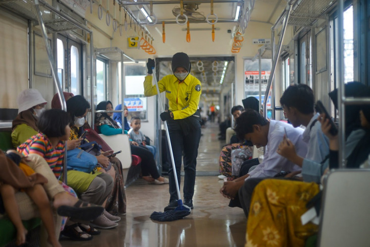 A worker from an outsourced cleaning service mops the floor of a Commuter Line train on Dec. 15, 2023, at Juanda Station in Gambir, Central Jakarta.