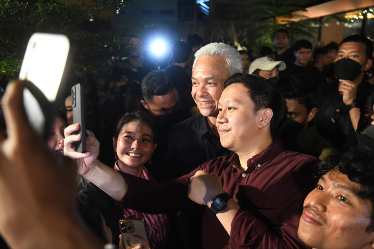 Presidential candidate Ganjar Pranowo (center) poses for a selfie after attending a dialogue with young voters in Bekasi, West Java, on Dec. 15, 2023. During the event, the former Central Java governor heard the concerns of young people, such as challenges in applying for jobs and opening new businesses.