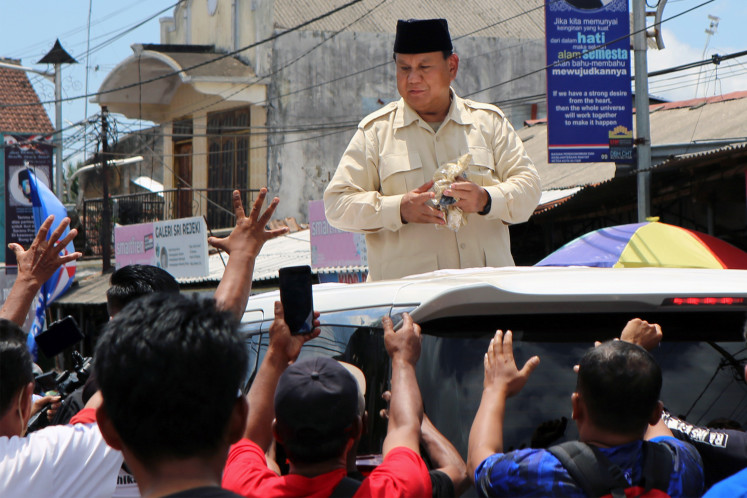 Supporters wave and take photos of presidential candidate Prabowo Subianto on Dec. 17, 2023, as he stands from an open sunroof of a car while en route to the grave of first president Sukarno in Blitar, East Java, a key battleground province in the Indonesian elections. 