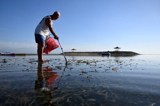 Australian national Paul Gibson collects plastic waste along a beach in Sanur, Bali on Dec. 18, 2023.
