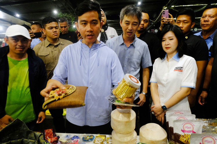 Vice presidential candidate Gibran Rakabuming Raka (third left) looks through the merchandise being peddled by local small and medium enterprises (SMEs) at the Warung Kopi Aming cafe in Pontianak, West Kalimantan on Dec. 17, 2023, on the sidelines of a meet and greet with creative economy practitioners from the region. Besides canvassing ideas for developing the local creative economy sector, Gibran spoke about the Nusantara capital city development.