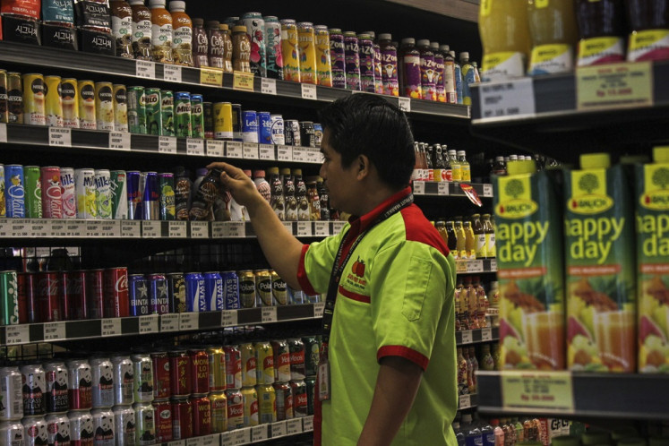 A worker arranges sweetened drinks in a supermarket in Jakarta on Dec. 14, 2023.