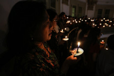 Churchgoers hold candles during a Christmas Eve service at the GPIB Immanuel protestant church in Jakarta on Dec. 24, 2023.