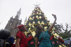 Congregation members take selfies with a Christmas tree before Christmas mass at the St. Mary of the Assumption Cathedral, popularly known as the Jakarta Cathedral, in Jakarta on Dec. 25, 2023.