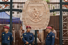 Security personnel stand in front of the logo of the General Elections Commission (KPU) in Jakarta on Nov. 13, 2023. 