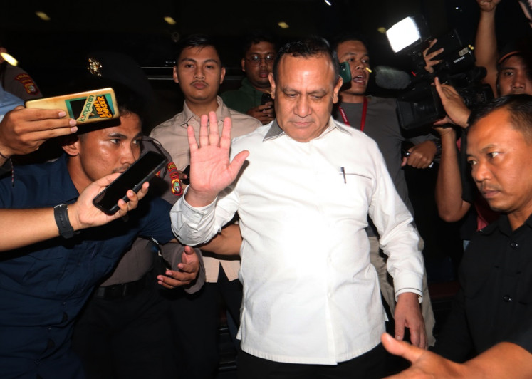 Firli Bahuri (center), the suspended Corruption Eradication Commission (KPK) chair, gestures to reporters on Dec. 21, 2023 while leaving the offices of the KPK supervisory council in Jakarta.