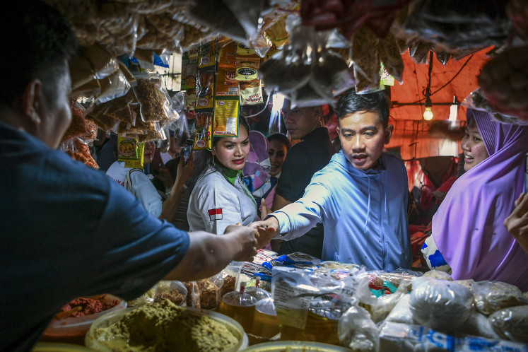 Vice presidential candidate Gibran Rakabuming Raka (second right) talks to vendors at the Pasar Minggu traditional market in Jakarta on Dec. 23, 2023.