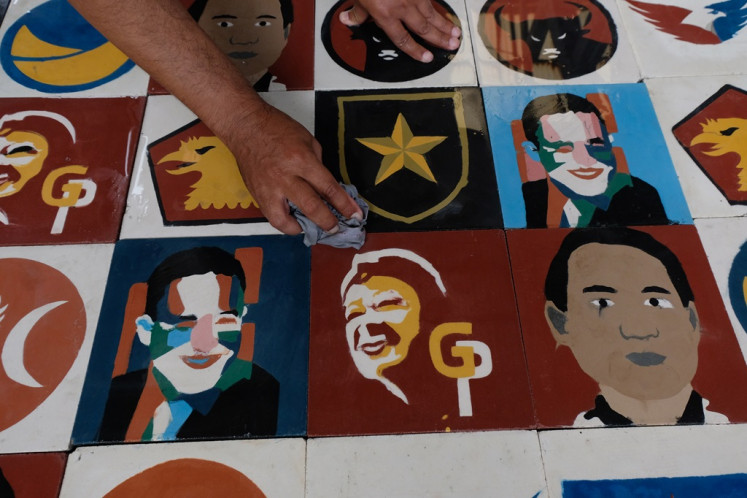 A worker cleans ceramic tiles showing the faces of presidential candidates and political parties participating in the 2024 general election in Magelang, Central Java on Dec. 4, 2023.