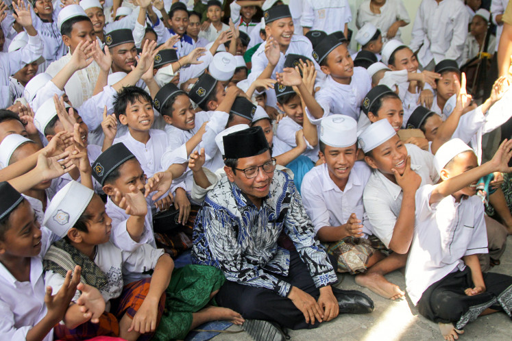 Vice presidential candidate Mahfud MD poses for a photo with students of Al-Khoziny Islamic boarding school in Sidoarjo, East Java, during his visit on Dec. 28, 2023. As a proud Islamic school graduate, Mahfud has expressed his commitment to providing state salaries for Islamic school teachers.