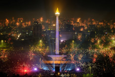 Fireworks explode over the city to usher in the New Year, as revelers gather around as the lit National Monument of Indonesia (Monas) in Jakarta on December 31, 2023. 