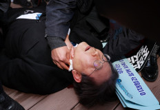 South Korean opposition party leader Lee Jae-myung is attended to after being attacked in Busan on January 2, 2024. South Korean opposition party leader Lee was stabbed in the neck on January 2 by a man who pushed through a crowd pretending to be his supporter. 