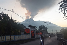 Motorists ride as mount Lewotobi Laki-Laki spews hot smoke in Flores Timur, Nusa Tenggara, Timur province on January 2, 2024.