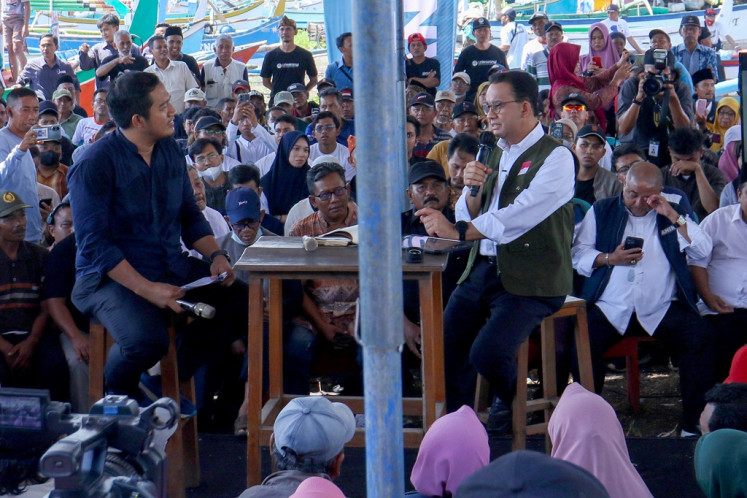 Presidential candidate Anies Baswedan (right, at table) talks with a fisherman on Dec. 28, 2023 during a campaign event at Blimbingsari Beach in Banyuwangi, East Java.
